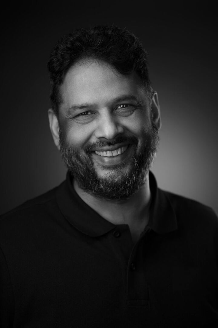 Black and white headshot of Daksh Kumar, smiling, in a dark polo shirt